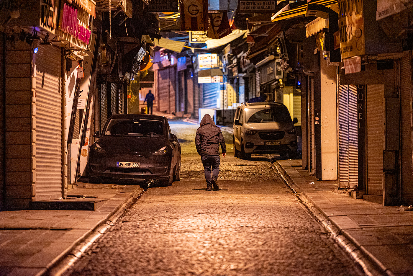 A man walking down a alley with parked cars